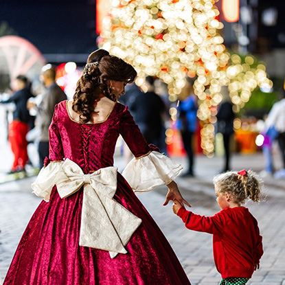 Princess in red holiday dress walking with girl in red sweater